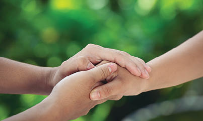 Couple holding hands in green meadow.
